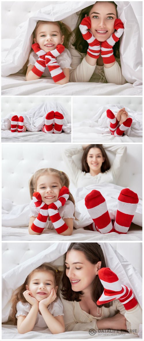 Cheerful little daughter and mom on bed stock photo